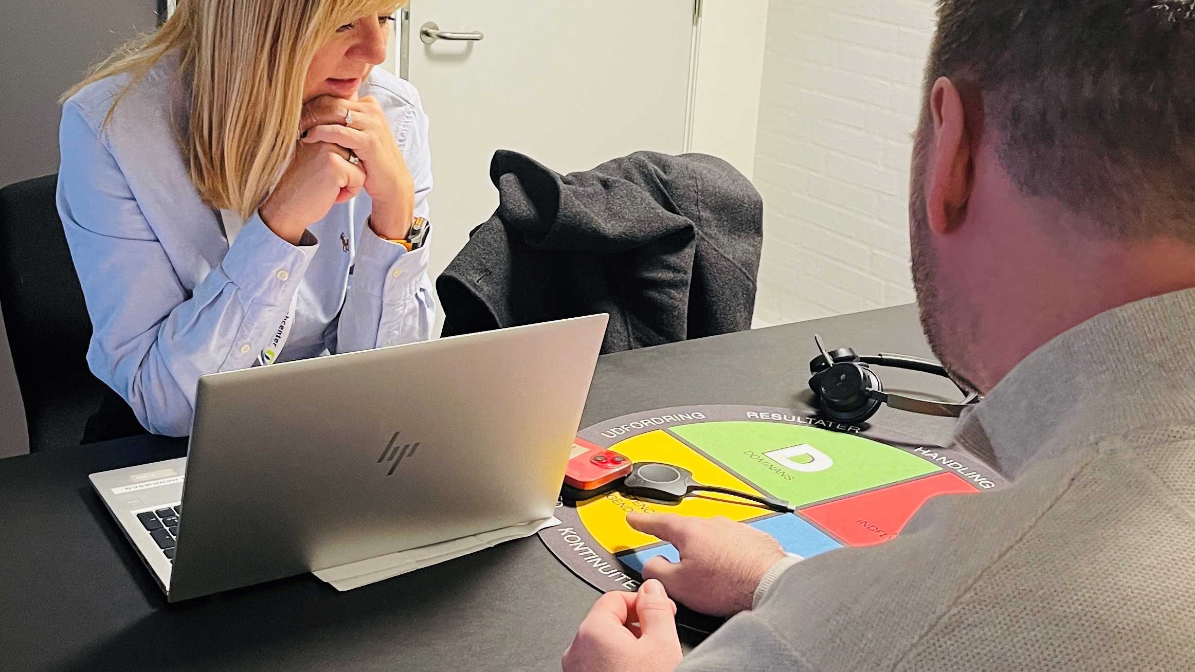 Mand peger på materialer på bord hos Socialrådgiver Helle