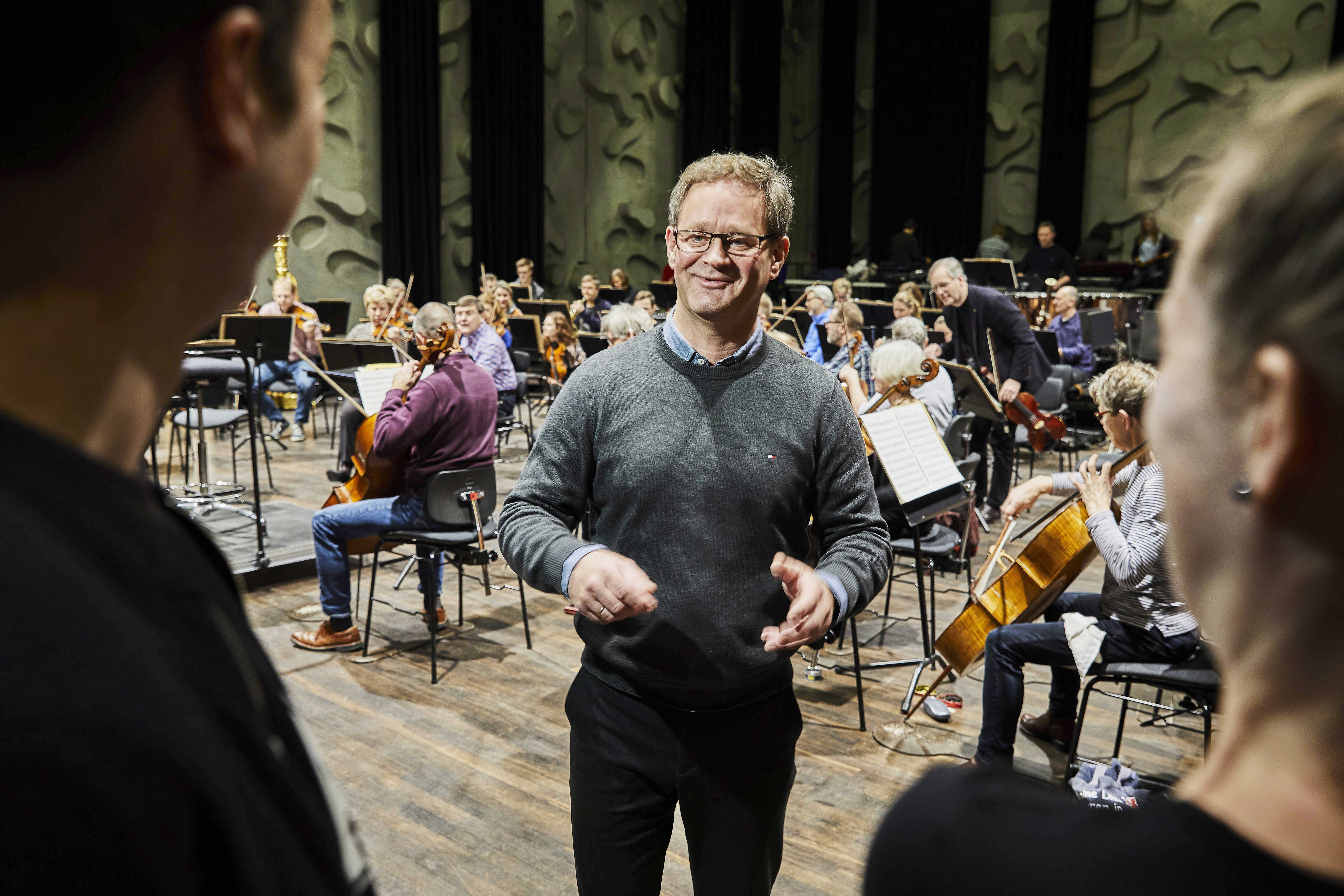 Mand i samtale foran et orkester