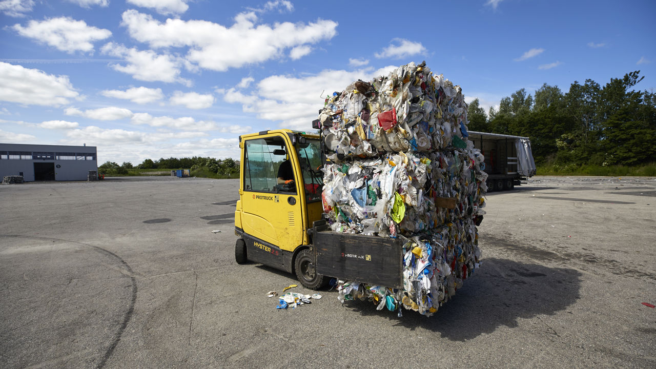 Gul truck med paller af komprimeret plasticaffald