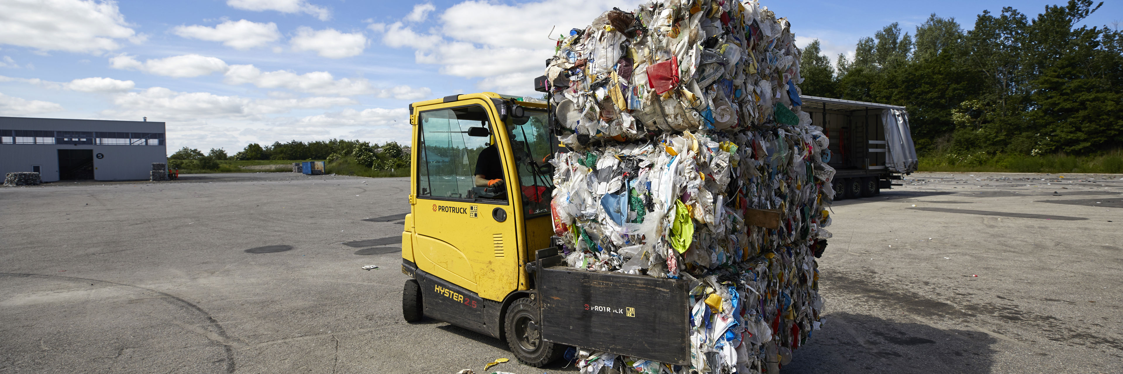 Gul truck med paller af komprimeret plasticaffald