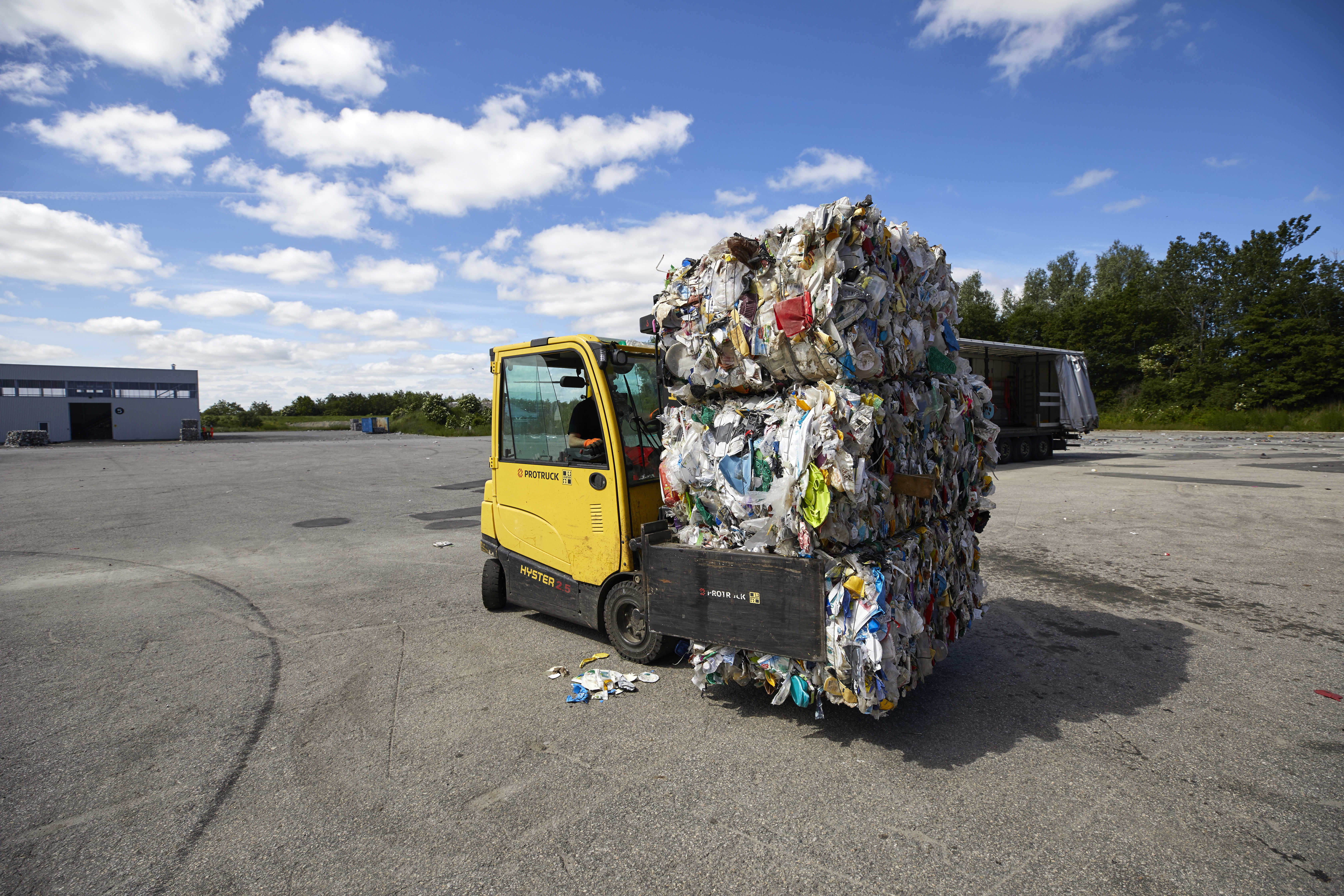 Gul truck med paller af komprimeret plasticaffald