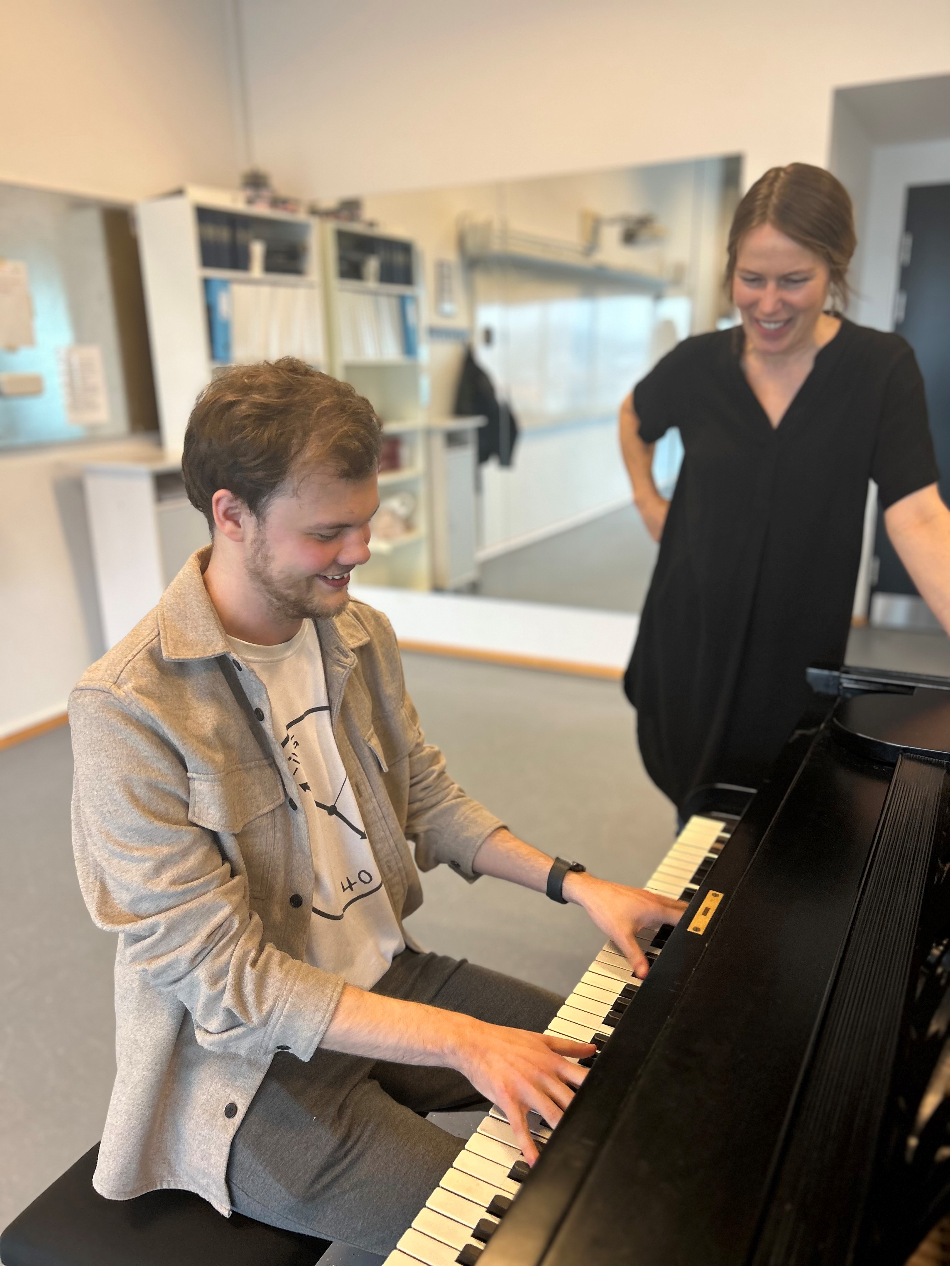 Mand spiller klaver mens kvinder kigger på