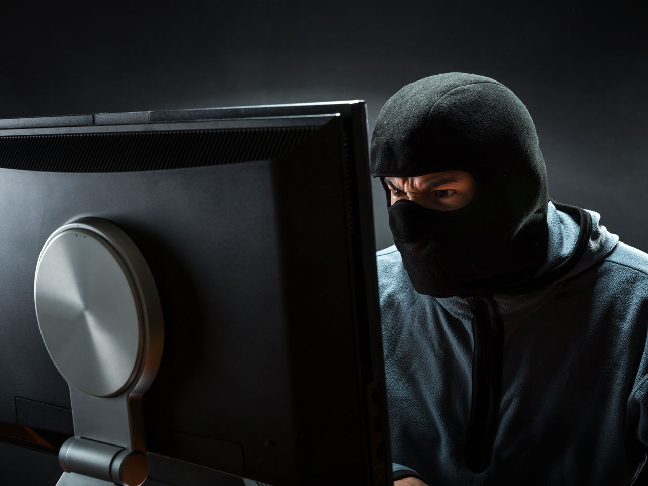 Maskeret person sidder ved PC