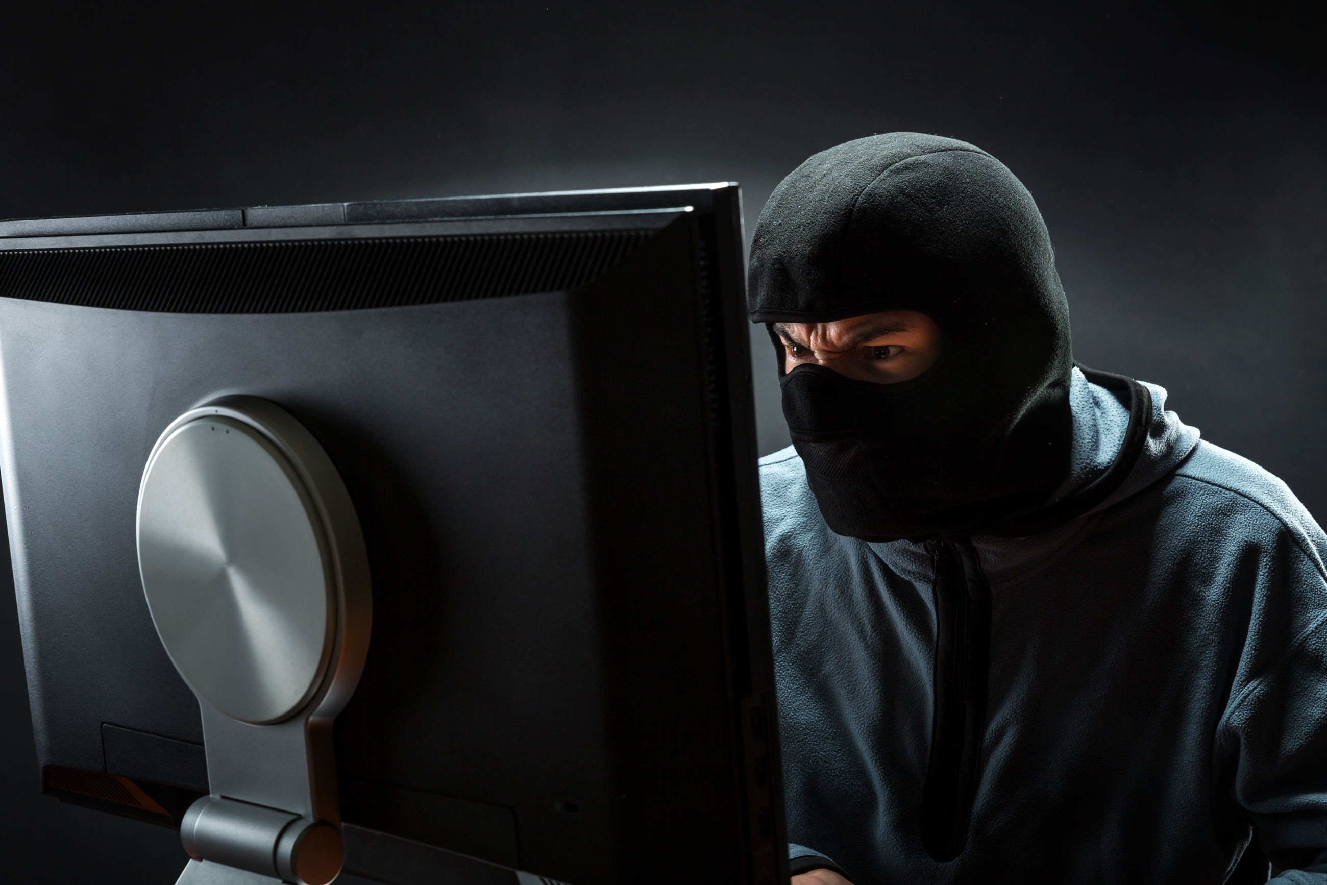 Maskeret person sidder ved PC