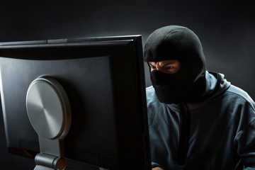 Maskeret person sidder ved PC