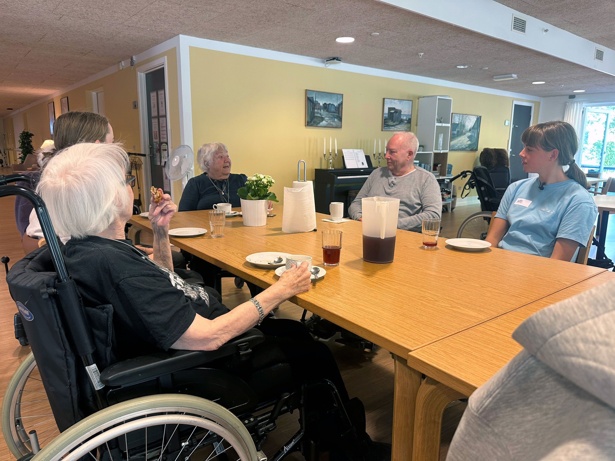 Lilly, Benny og Mie får kage og saftevand i fællesrummet sammen med andre beboere og elever fra valgfaget Gør en forskel