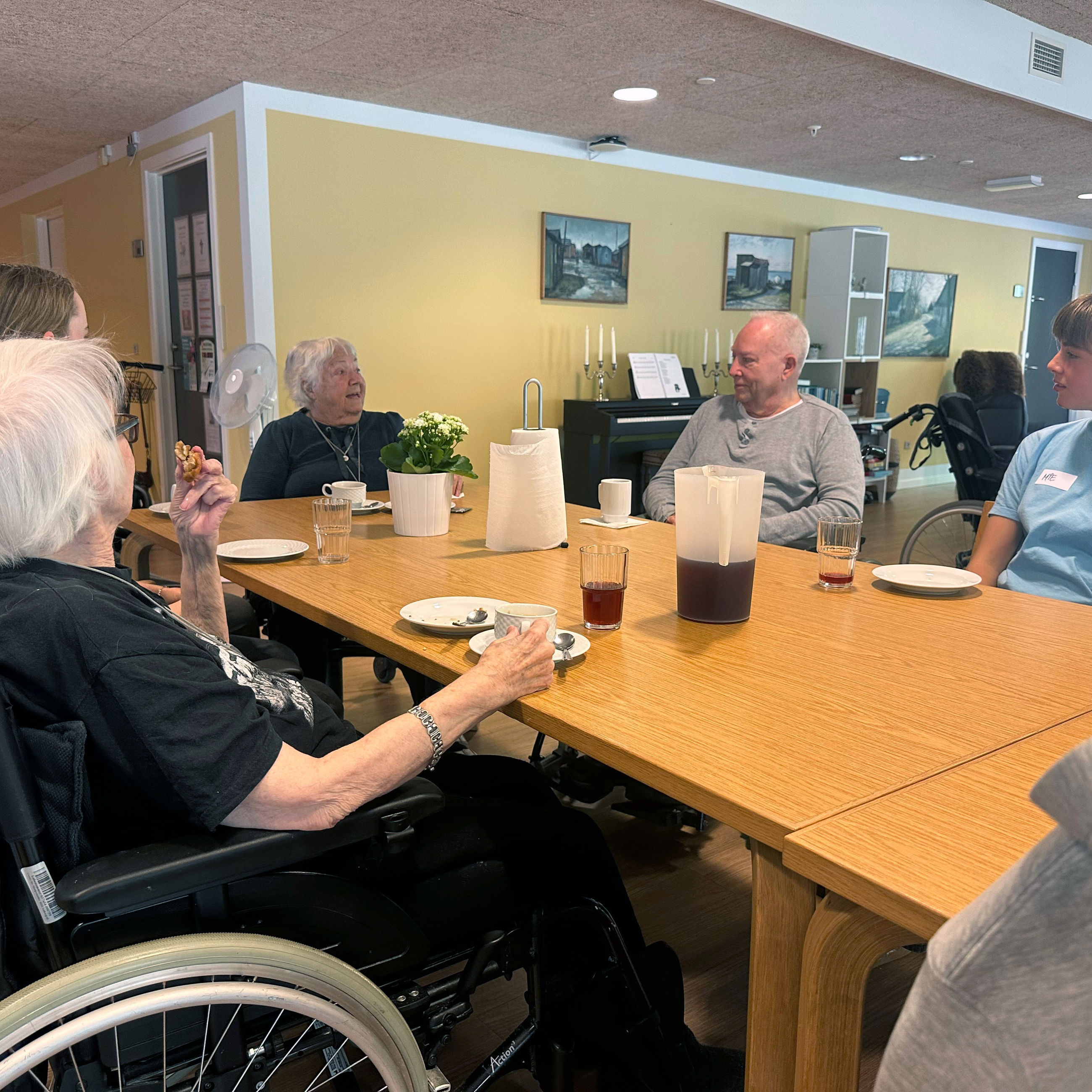 Lilly, Benny og Mie får kage og saftevand i fællesrummet sammen med andre beboere og elever fra valgfaget Gør en forskel