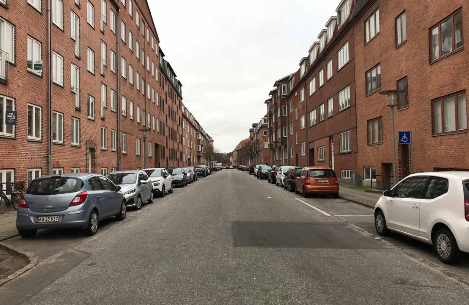 Gade i Vestbyen med kantstensparkerede biler.