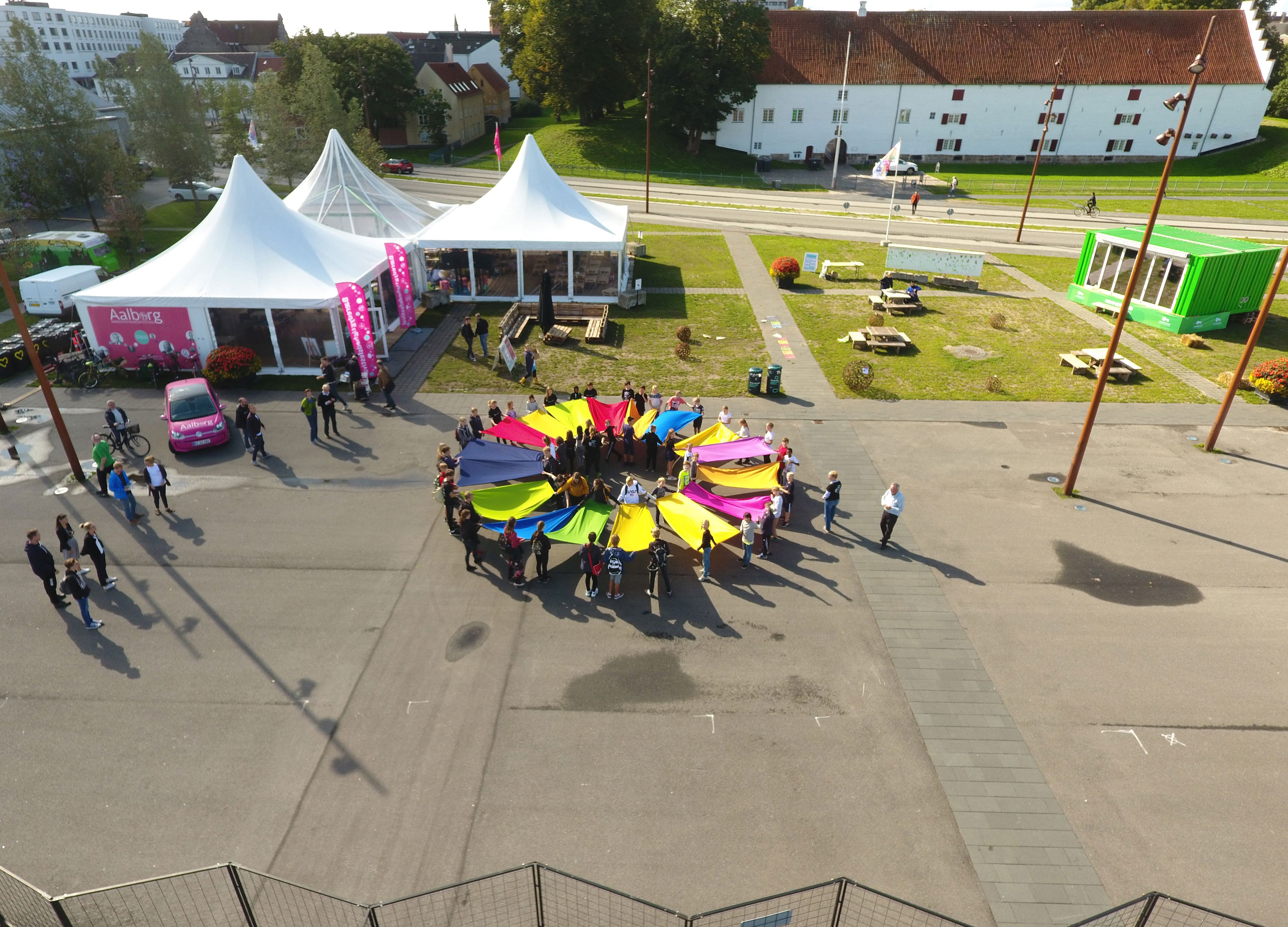 Mennesker, der holder flag i en cirkel, som danner FN's bæredygtighedsmål