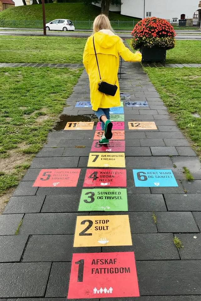 Pige i gul regnfrakke, der hopper i hinkerude på FN's Verdensmål