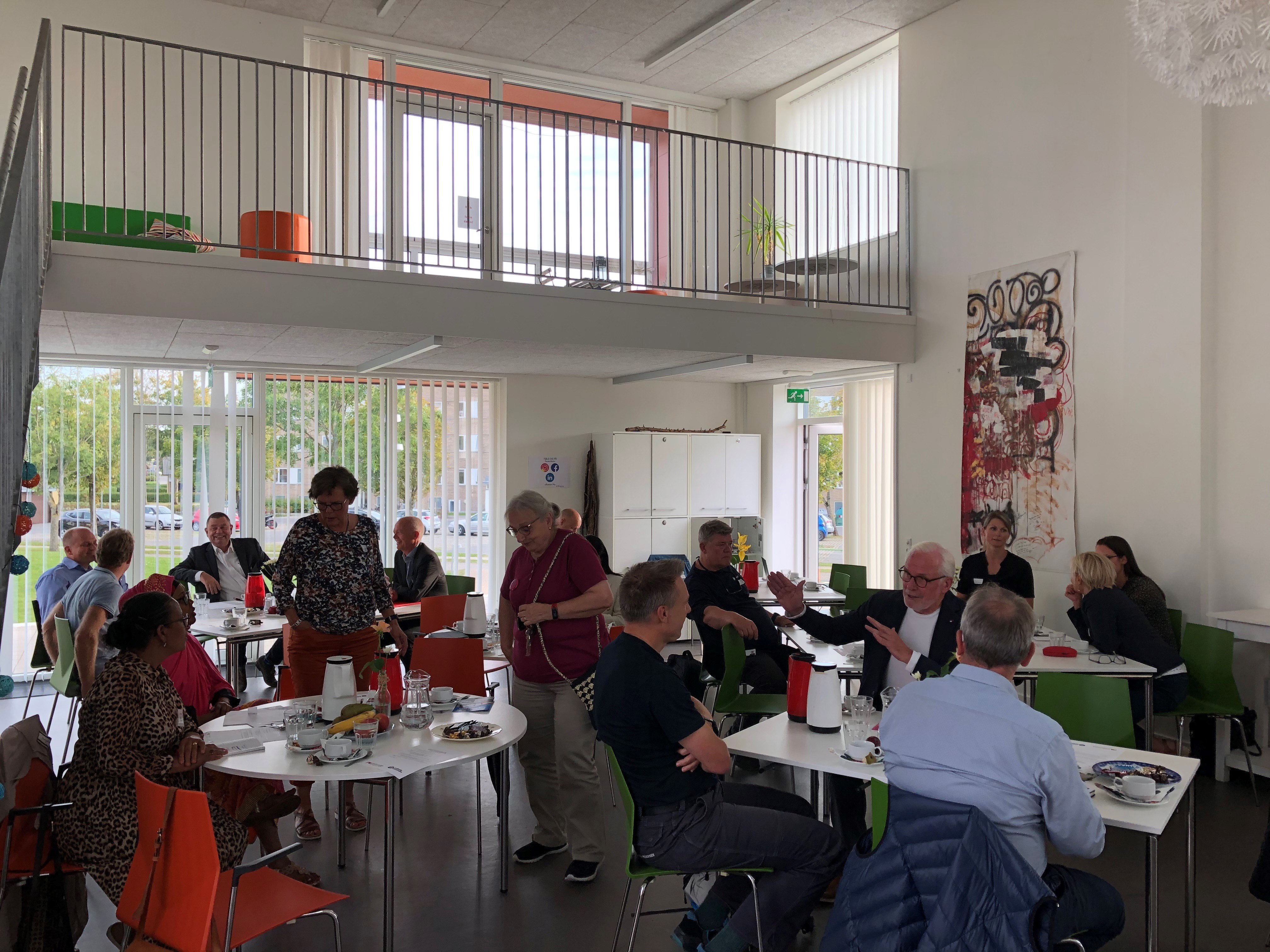 Personer i stort rum omkring borde