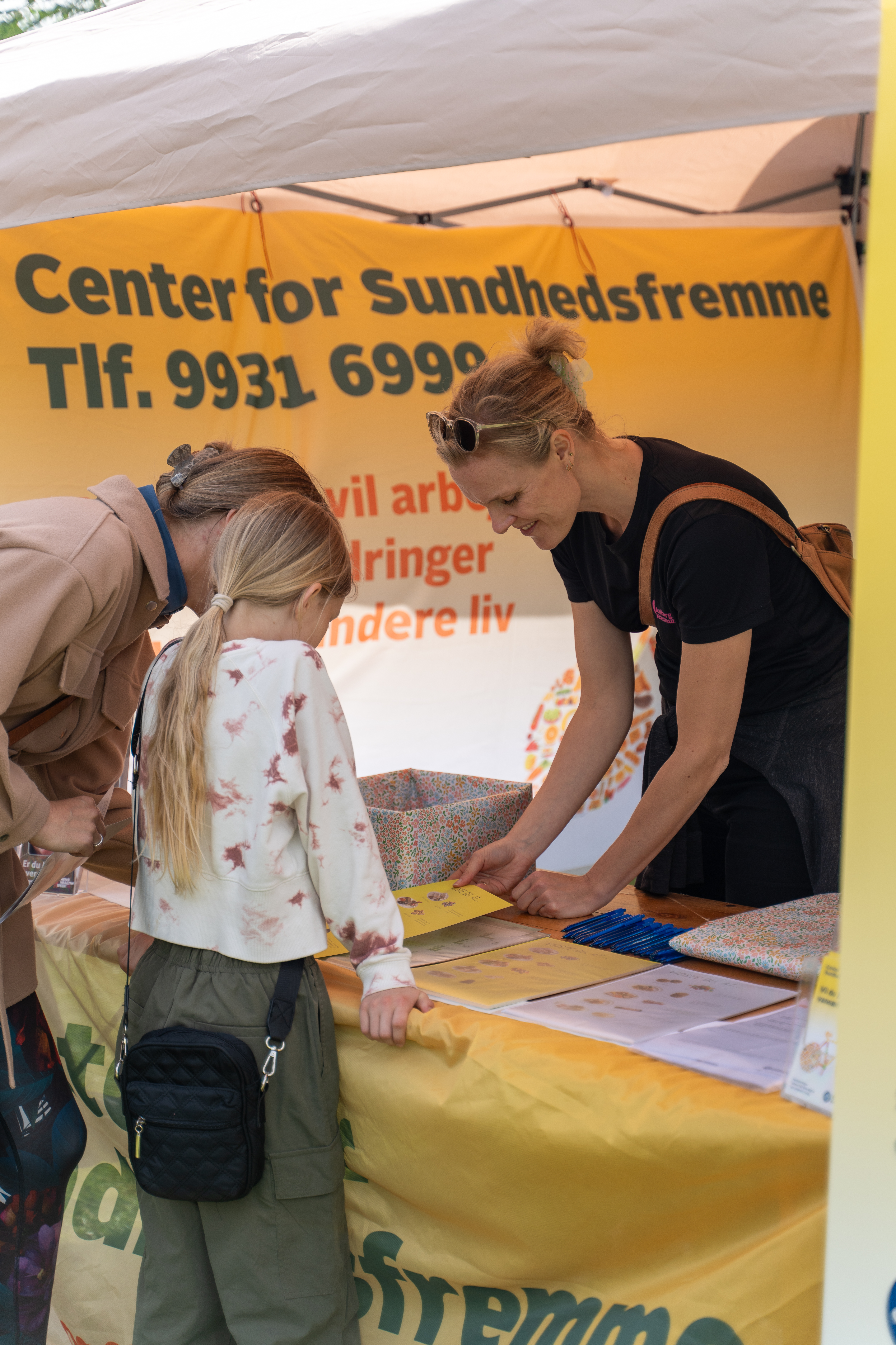 Kvinde og barn kigger materiale i en bod