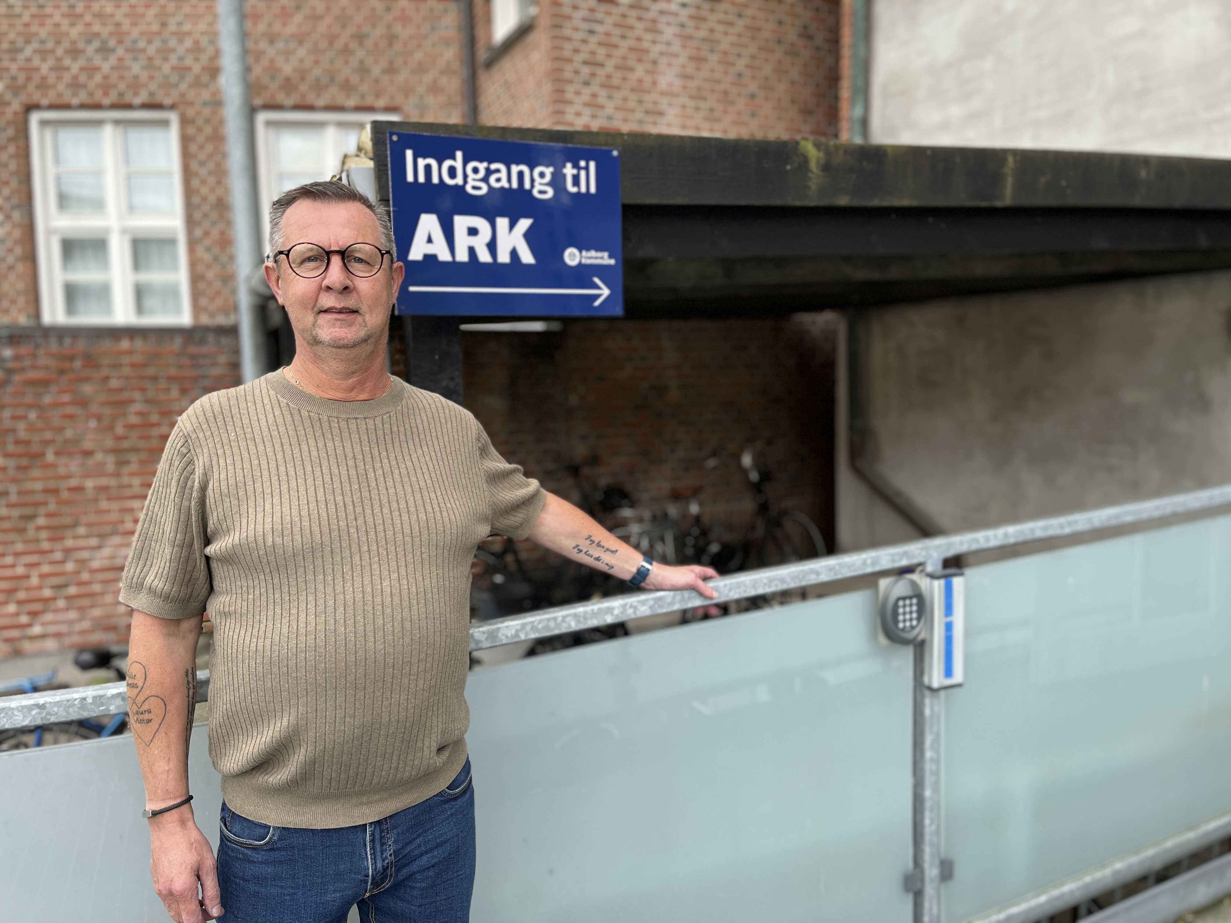 Bent fra Ark - bagved ham er et skilt hvor der står indgang til ARK