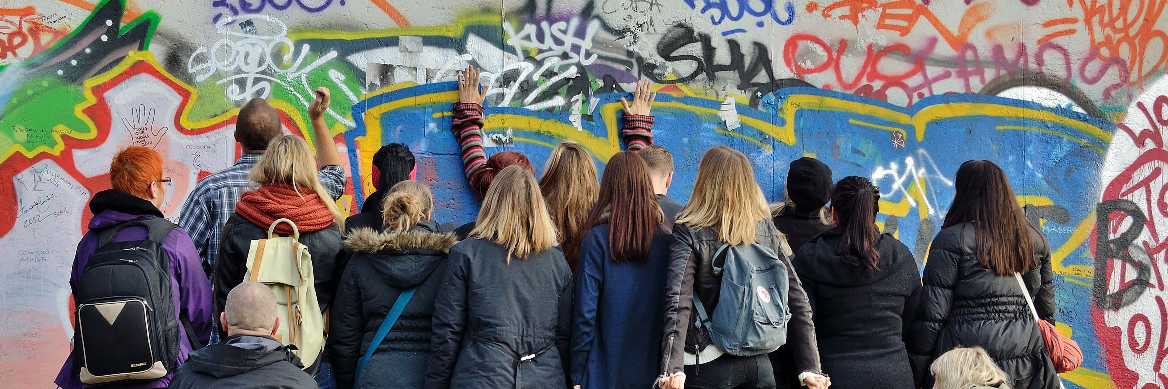 Gruppe af unge står med ansigterne mod mur og betragter graffitti
