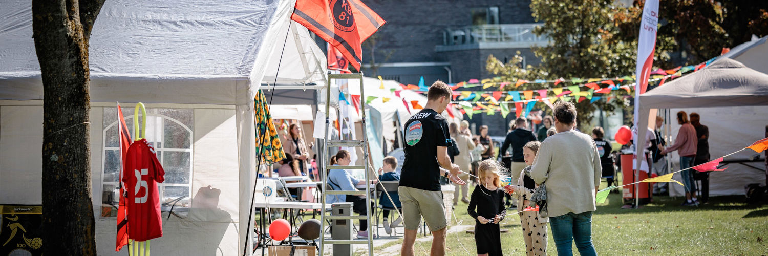 Telte og mennesker til byfest på græs.