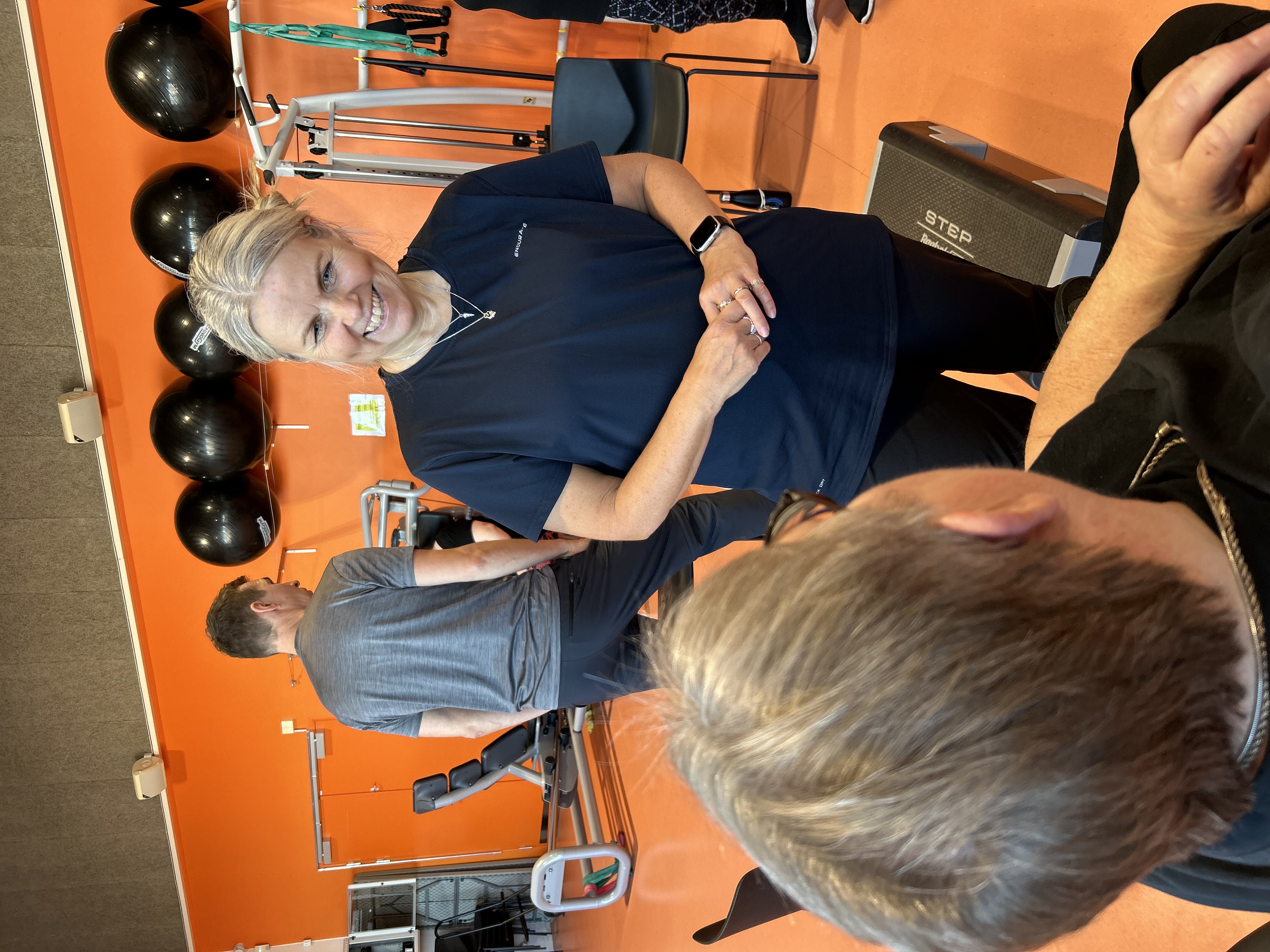 Stående kvinde taler med siddende i en træningssal