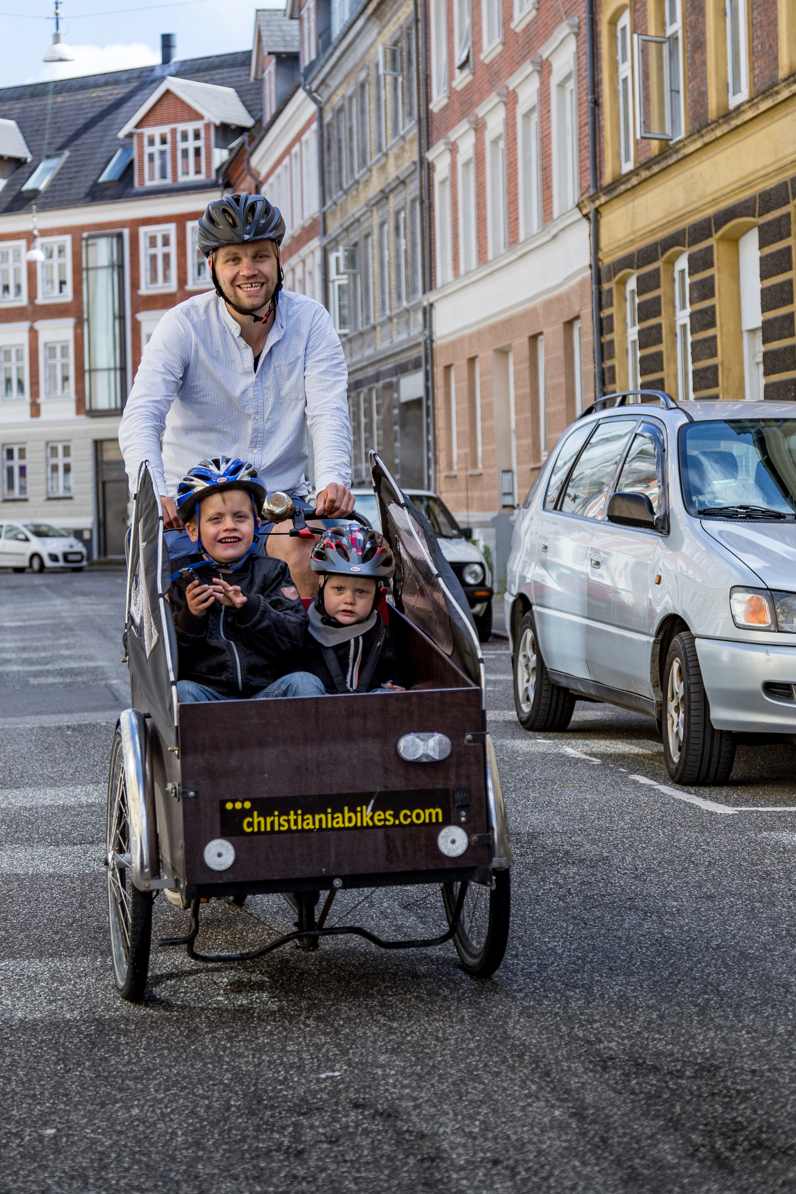 Mand cykler med børn i en ladcykel