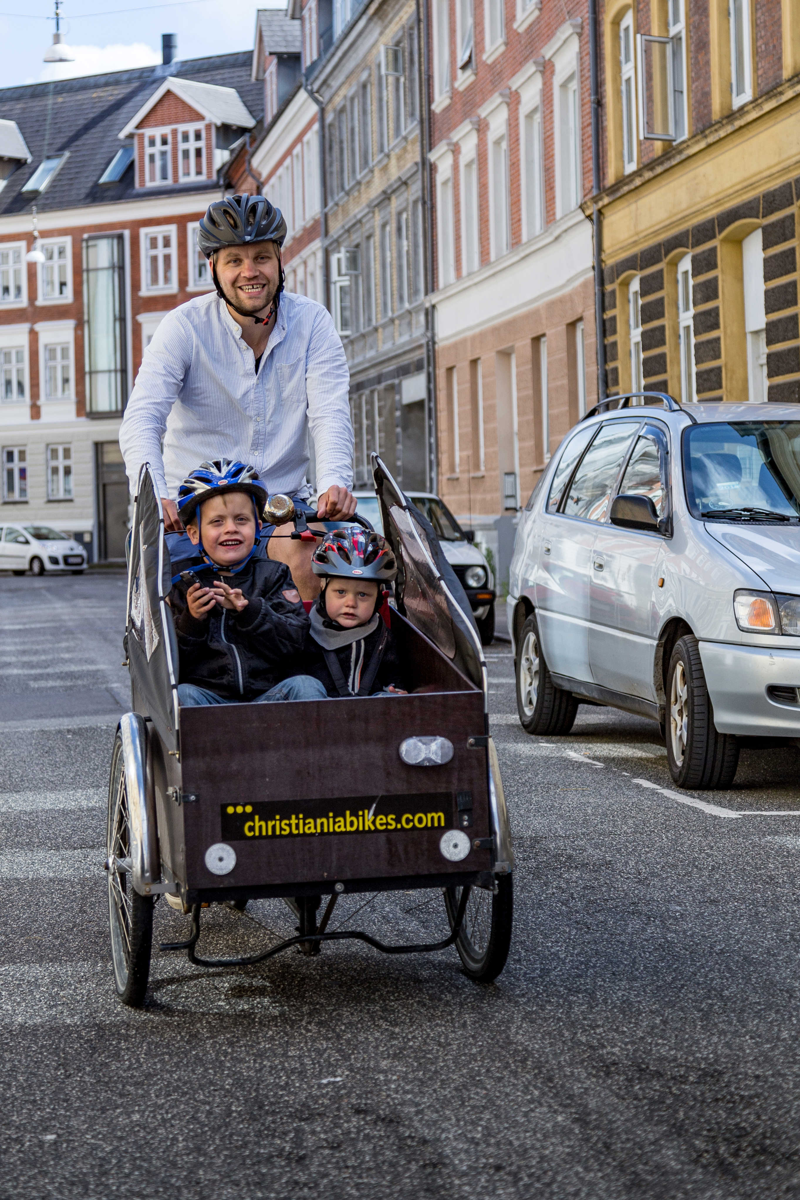 Mand cykler med børn i en ladcykel