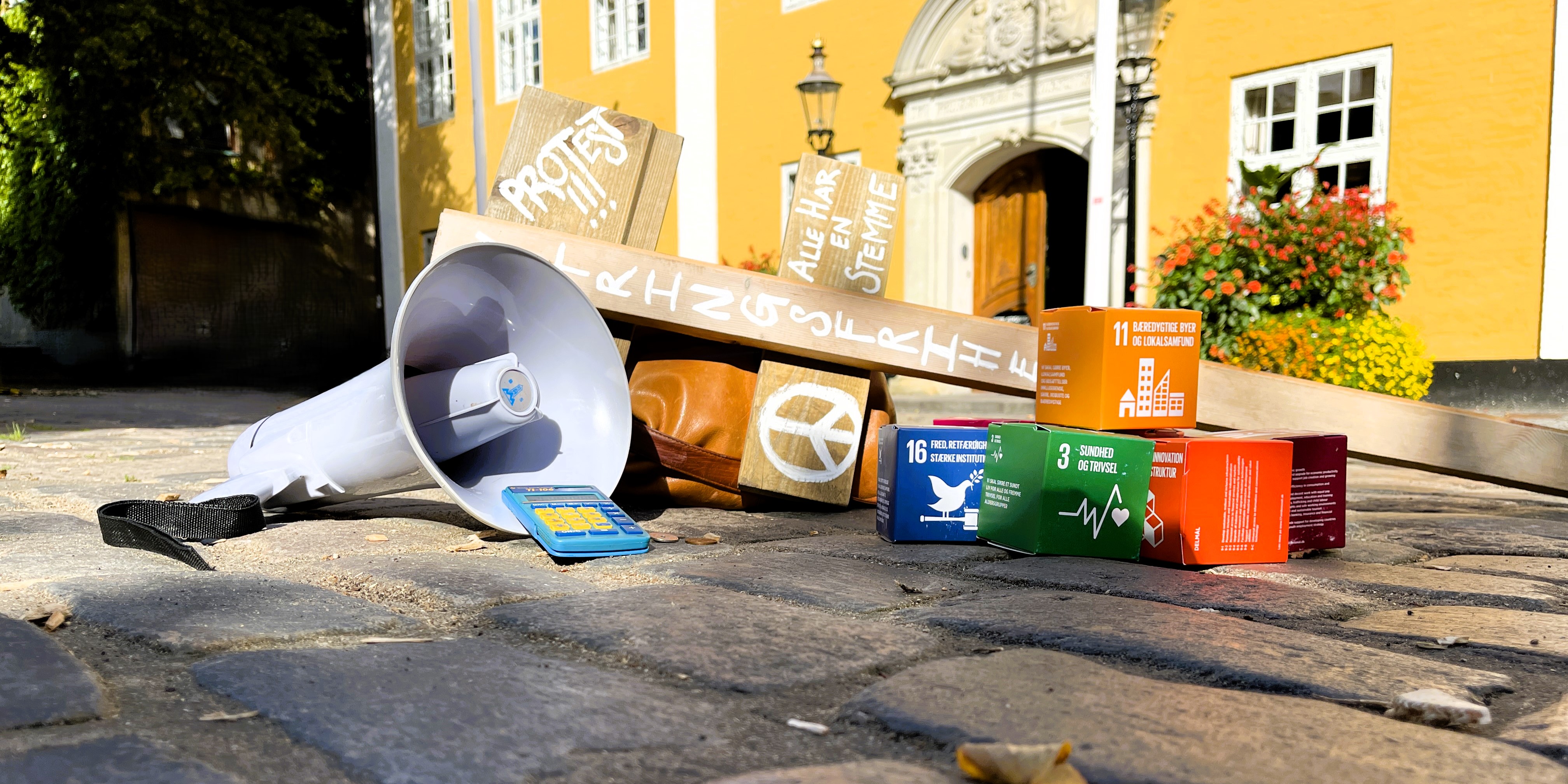 Megafon, verdensmål og skilt for demokrati foran rådhuset