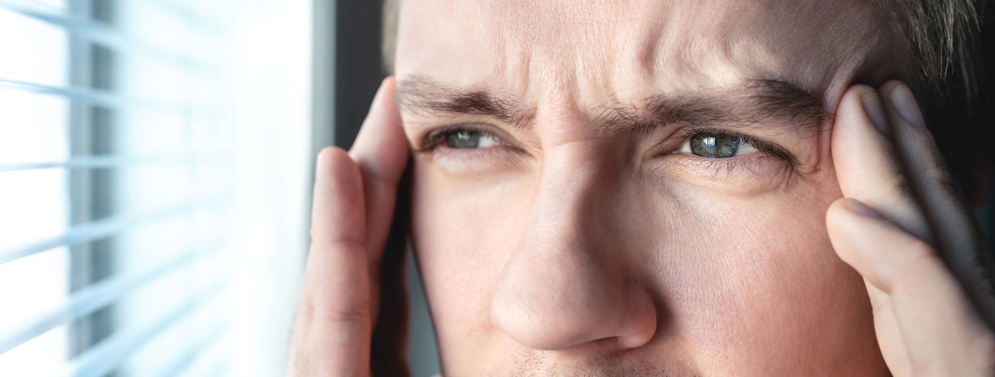 Mand der holder begge hænder op til tindingen