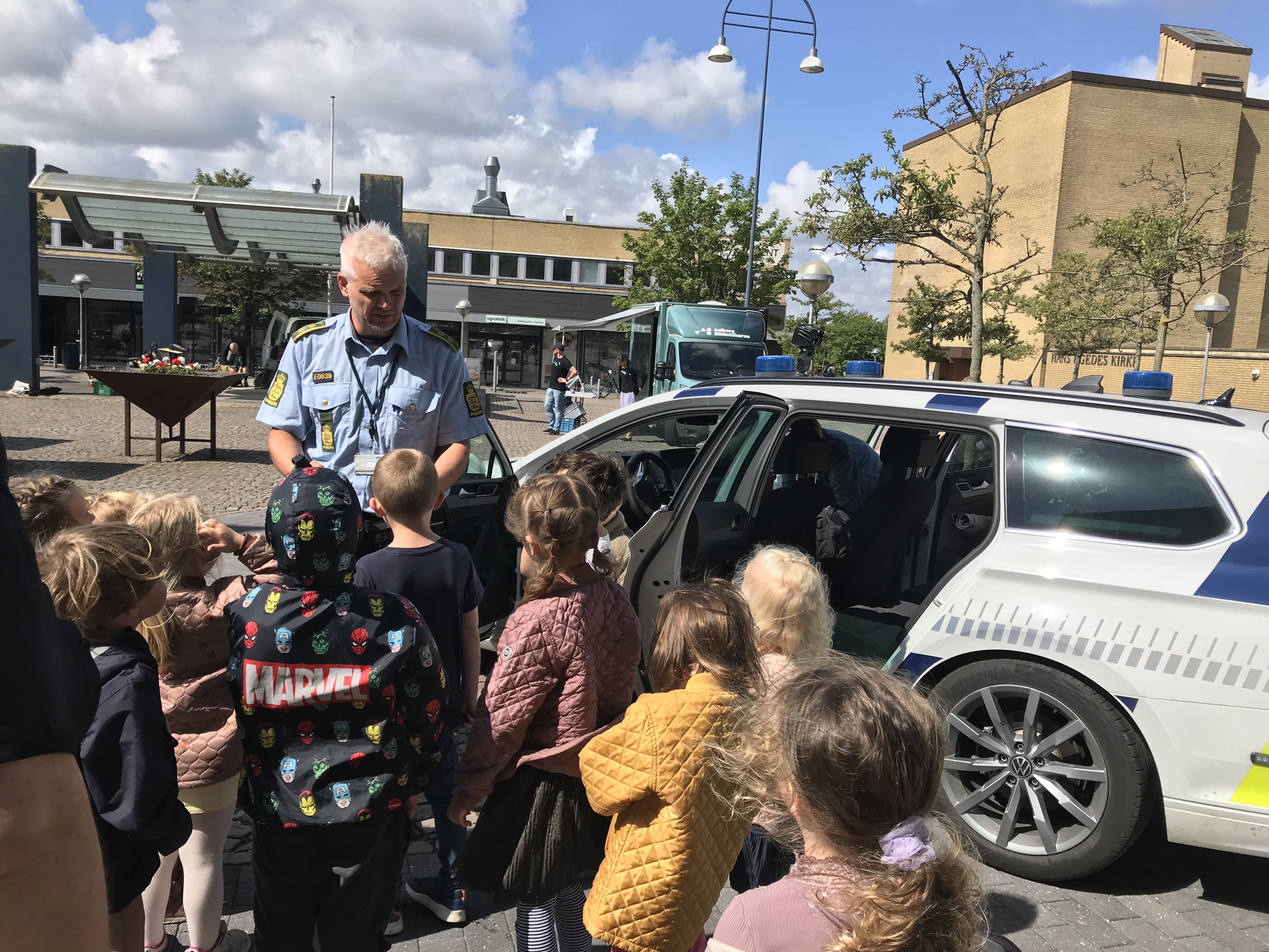 Politimand ved politibil sammen med børn