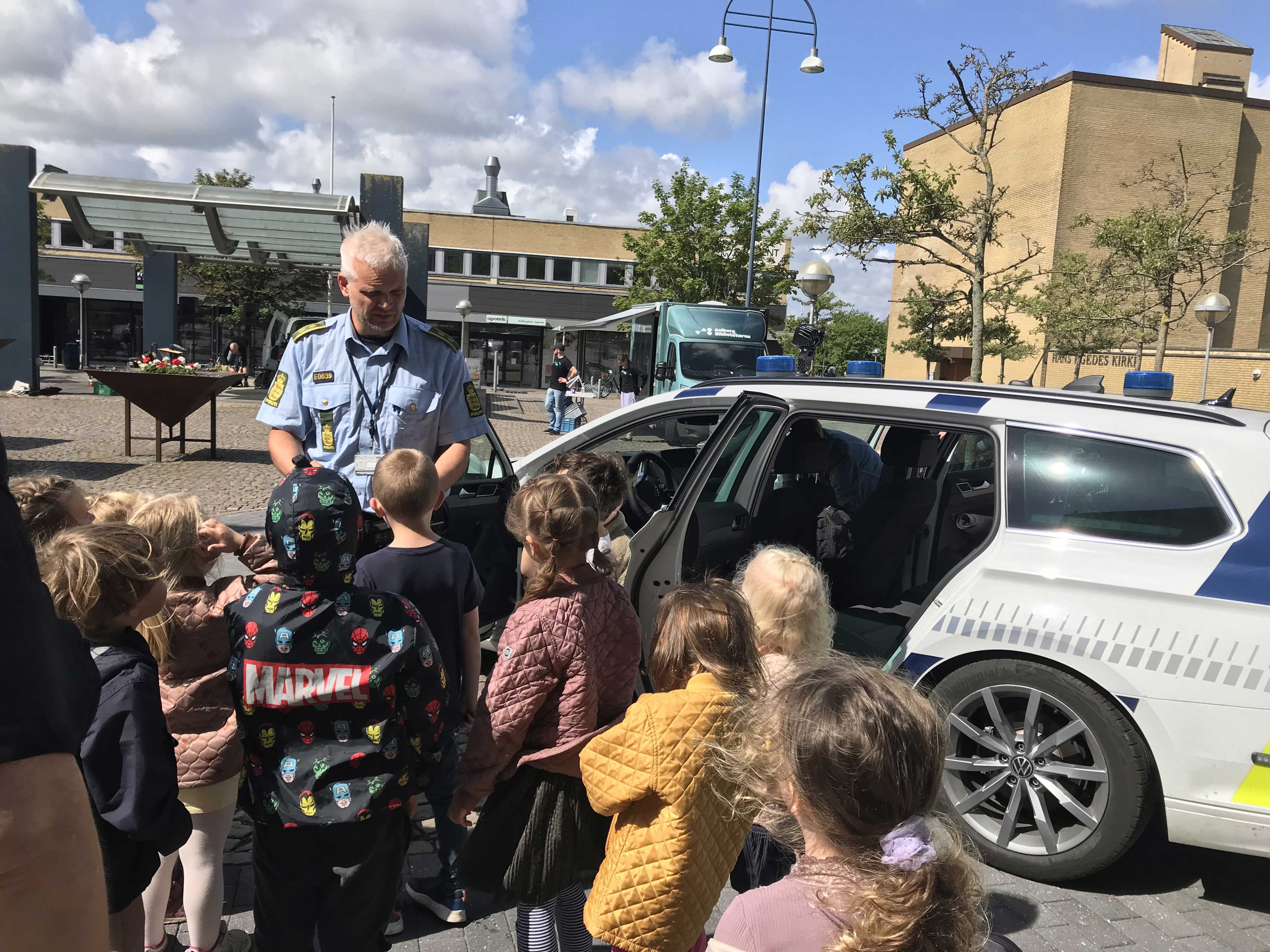 Politimand ved politibil sammen med børn