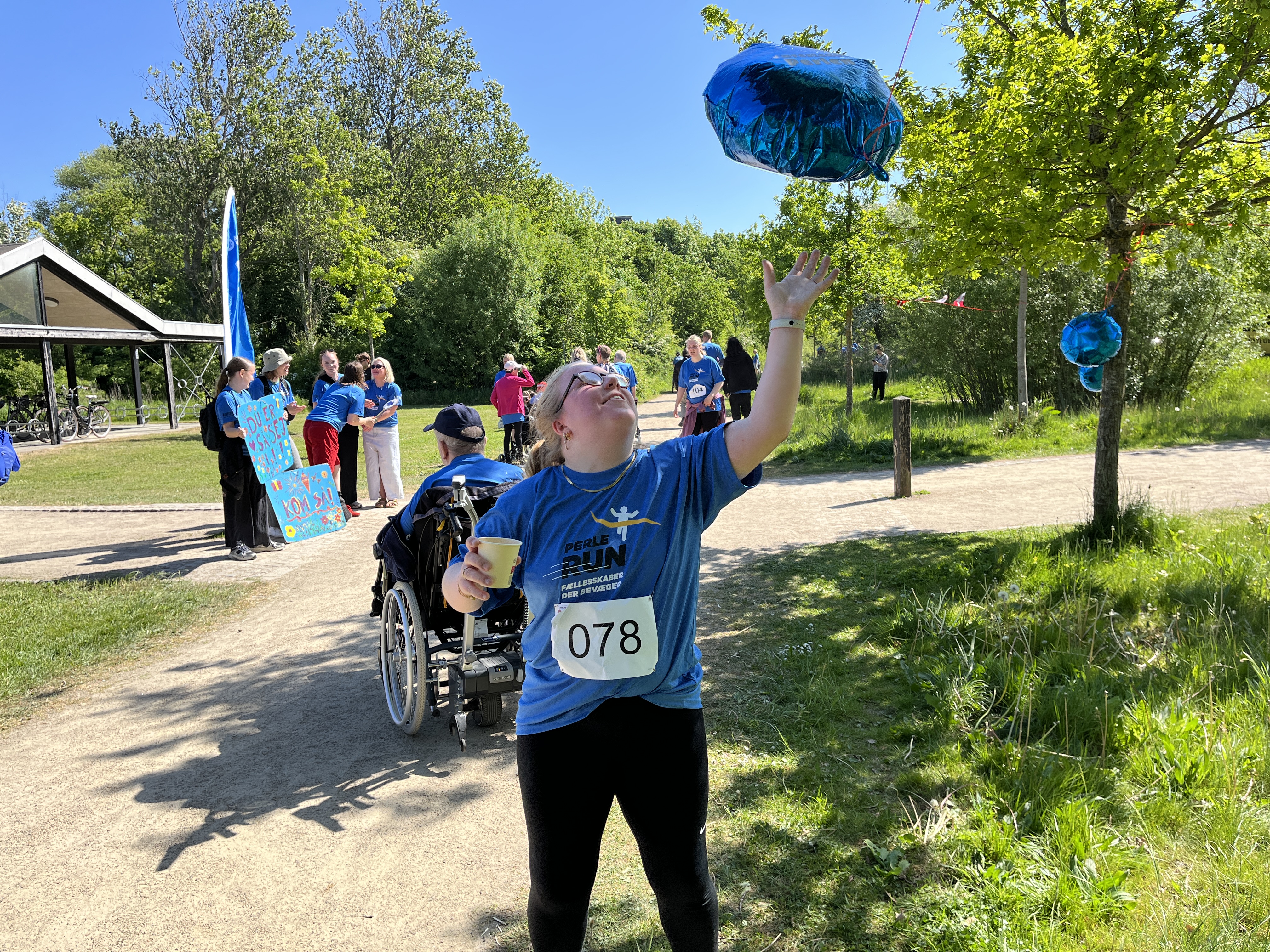 Silje står med en perlerun t-shirt og slår til en blå flot ballon